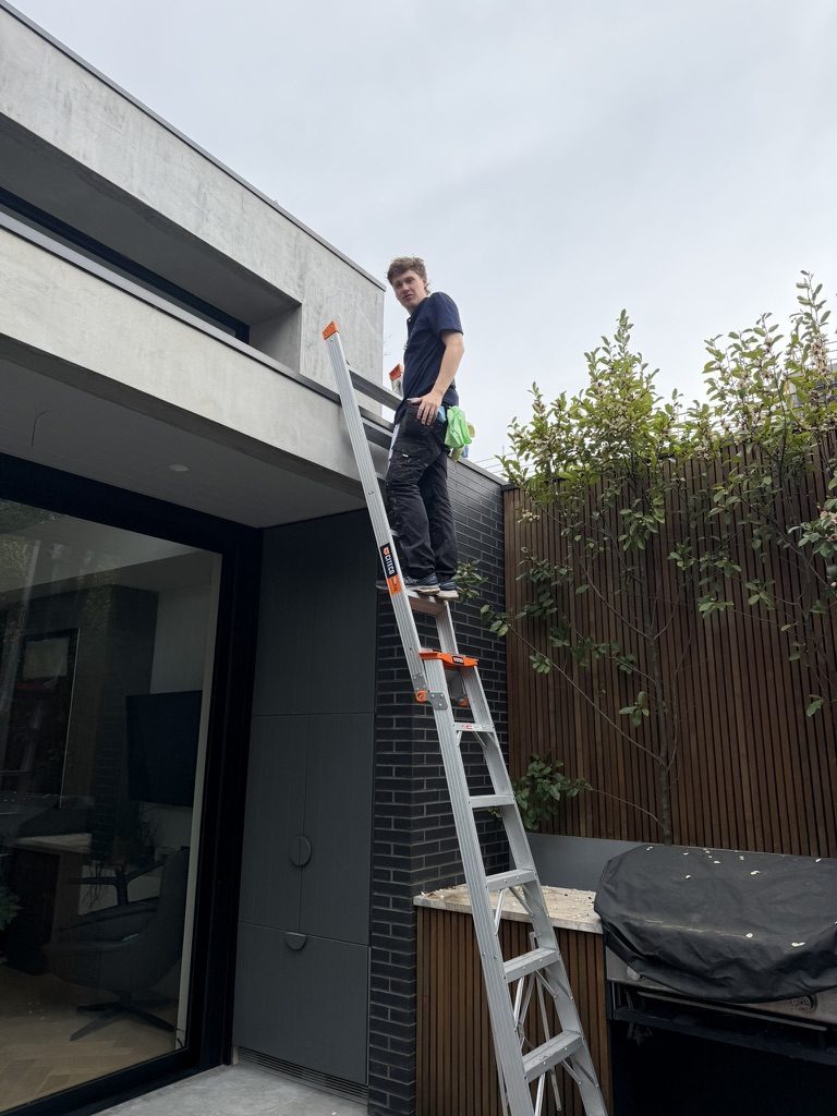 Cleaning a high exterior window from a ladder